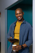 © Wavebreak Media - African American man standing in office hall holding tablet and coffee cup wearing sweater
