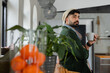 © Wavebreak Media - Indian man leaning at wooden counter in kitchen holding white mug wearing knit beanie, copy space