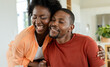 © Wavebreak Media - African American couple laughing and embracing in home kitchen with wooden table and clear glass