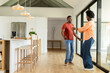 © Wavebreak Media - African American couple dancing joyfully on hardwood floor near sliding glass doors with orchid