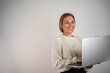 © Nenad - Confident business woman smiling holding laptop isolated on grey background