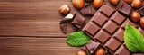 A chocolate bar with mint leaves and nuts on a wooden table