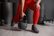 © New Africa - Woman exercising with kettlebell near dark wall indoors, closeup