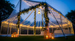 © Sheikh - Magical clear top wedding tent illuminated by warm fairy lights and floral garlands creating a romantic atmosphere for an outdoor celebration at dusk