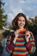 © SHOTPRIME STUDIO - Woman smile sunglasses striped sweater portrait outdoors casual young adult holding sunglasses in colorful knitwear, short hair in natural daylight, happy expression and relaxed lifestyle vibe.
