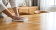 © Achmad - Dedicated hands meticulously wiping a wooden dining table, ensuring a pristine and hygienic surface in a modern home environment