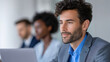© CoreVisuals - Modern office business work space vibe with focused young man laptop suit, thoughtful expression, clean light interior, teamwork background, contemporary corporate setting, productivity and calm