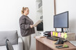 © Svetlana Radayeva - Caucasian woman working from home, planning and writing notes at a wooden desk with a computer monitor, showcasing a casual remote office setup.