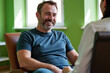 © Alex & M Studio - Handsome middle aged man smiling and looking at female colleague while sitting in leather chair during casual meeting or interview in green office room interior