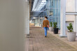 © Wavebreak Media - Male student walking along modern building walkway carrying red notebooks near planters, copy space