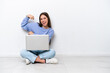 © luismolinero - Young caucasian woman with laptop sitting on the floor isolated on white background doing strong gesture