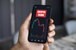 © DenPhoto - man hand hold phone with chart scam crypto coins screen