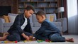 © Yuliia - Two cute African American children playing with toys on floor at home enjoying entertainment concentrated kids little friends siblings brothers boys play game happy family weekend hobby together joy