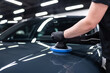 © Daniel Jędzura - Close-up of machine polishing on a glossy black car hood in a professional detailing studio, showing paint correction process, surface refinement and preparation for ceramic coating.