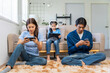 © amnaj - Family using smartphones and a tablet, each person focused on their own digital device, showing screen addiction and modern lifestyle