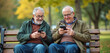 © Vadym - Two senior men use smartphones on bench. Friends relax in park, looking at screens. They wear glasses and jackets enjoy online content in retirement together using tech.