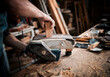 © Beatriz - hands of a young man carpenter, craftsman and entrepreneur sanding a handmade piece of wood in the workshop