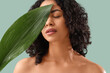 © Pixel-Shot - Young African-American woman with palm leaf on green background, closeup