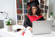 © Pixel-Shot - Pretty African-American female graduate with laptop sitting at table in library