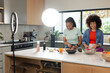 © Wavebreak Media - Diverse female friends chopping vegetables on marble island in kitchen under ring light, copy space