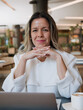 © Santiago - Professional mentor looking at the camera with hands clasped in front of the laptop, ready for an online coaching session.