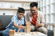 © itchaznong - Playtime Fun. Father and son playing Jenga, enjoying a competitive and engaging moment.