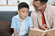 © itchaznong - Learning Together. Father reading a book with his son, fostering education and connection.