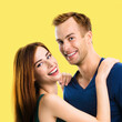 © vgstudio - Happy smiling cute couple. Portrait of standing close, hugging boyfriend, girlfriend in love studio concept, isolate over yellow color background. Young man and woman posing together. Square image