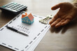 © alexkich - Home Insurance Policy Document with Hand Holding Keys and Miniature House on Table