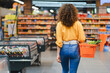 © Serhii - Woman walking through supermarket aisle carrying shopping basket