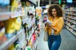 © Serhii - Woman comparing cleaning product label in supermarket aisle
