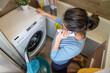 © Андрей Знаменский - the hostess calls the service to call a specialist for the repair of household appliances during the breakdown of the washing machine at home