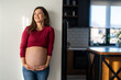 © NDABCREATIVITY - Happy pregnant woman with stretch marks and a beautiful smile in comfortable clothes showing belly