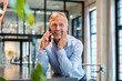 © BusinessClass by W61 - Smiling professional on mobile phone in modern office environment