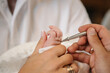 © Serhii - Baby hand. Unction at baptism. Anointing. Priest stretched hands to hand baby. Temple, Orthodoxy. Closeup of tiny baby hands, the sacrament of baptism ceremony. Godmother holds child.