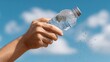 © Iaroslav - Hand holding cold plastic bottle with refreshing mineral water droplets against a vibrant blue sky, promoting healthy hydration