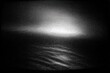 © Titus - Grayscale grainy image displaying an illuminated cloud formation over a dark, textured expanse