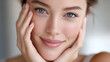 © GrayFrog - Smiling young woman with bright blue eyes, soft skin and natural, relaxed expression, gently touching her face.