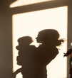 © Anna - Silhouettes of a mother and baby on a wall, shadows of people illuminated by the sun. Happy Mother's Day. Tender maternal feelings. The joy of motherhood, tenderness, caring for a child