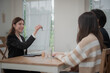 © surachetkhamsuk - Estate agent hands house keys to the client. Asian woman realtor gives keys to the couple buyer while sitting at a table with a house model. Real estate