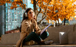© kinomaster - Young Woman Studying Outdoors With Headphones and Laptop