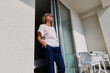 © Caterina Trimarchi - Blond woman opening a window and coming out on a hotel balcony enjoying the sun, admire seacoast view and breathing fresh sea air.