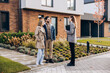 © Maria Vitkovska - Happy couple interacting with realtor outside modern new house on the street