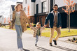 © Maria Vitkovska - Happy family walking holding hands in suburban neighborhood during autumn