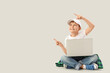 © Pixel-Shot - Little boy with laptop pointing at something on light background