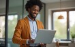 © li - Young smiling african man standing and using laptop. High quality