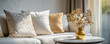 © Hathairat - Soft decorative pillows in neutral tones on cozy sofa with golden vase of dried flowers on round marble table, warm light