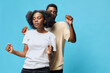 © SHOTPRIME STUDIO - A joyful couple dancing together against a soft blue background, showcasing playful emotions and contemporary casual fashion in a vibrant setting