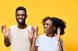 © SHOTPRIME STUDIO - Happy young African American couple celebrating with joy against a bright yellow background, expressing excitement in casual attire with playful emotions