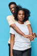 © SHOTPRIME STUDIO - Young African couple embracing against a blue background, expressing love and connection with casual clothing and natural hairstyles, showcasing joy and intimacy